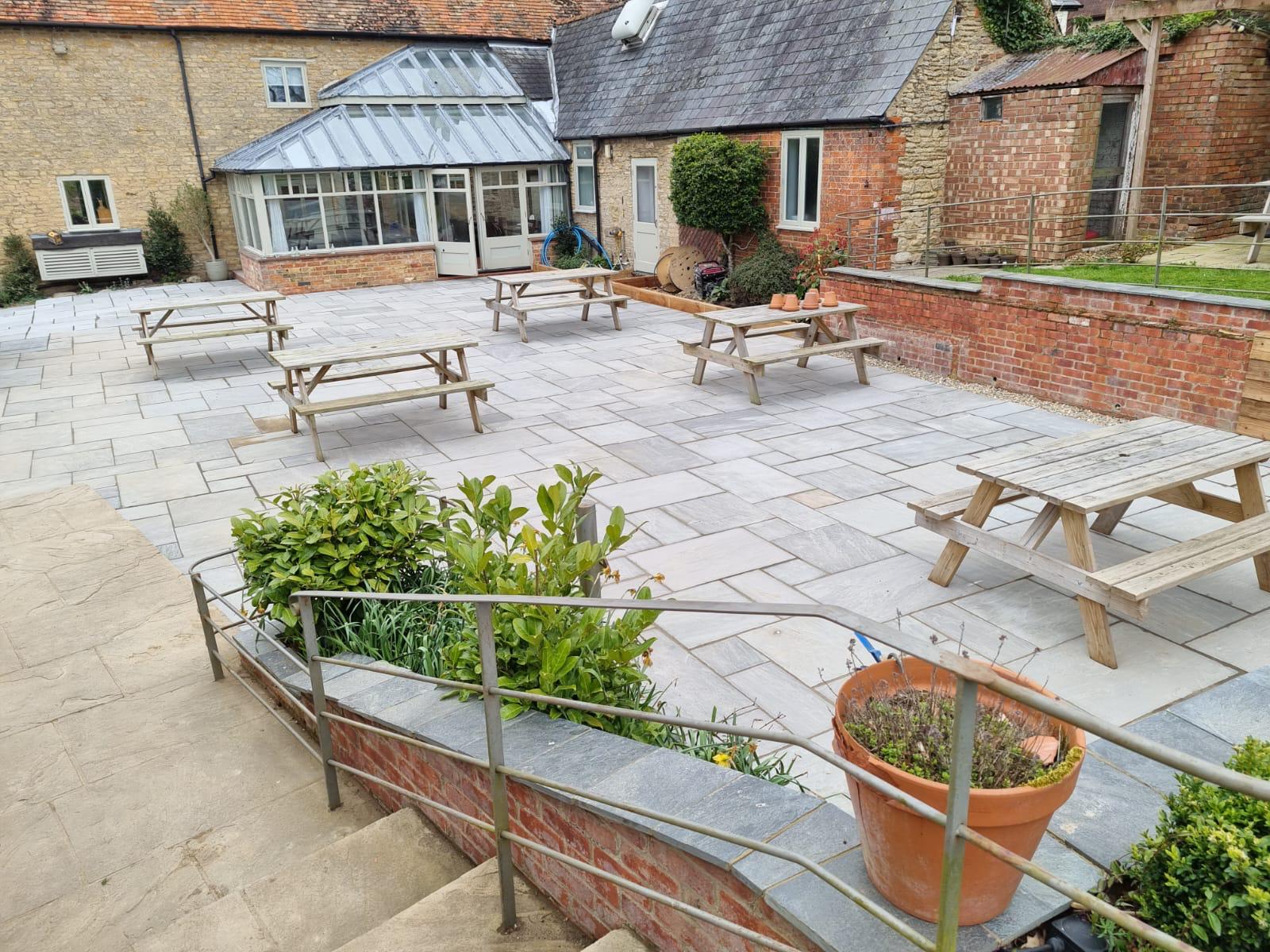 Contemporary garden in Bedford featuring natural stone paving, mature planting and a timber pergola, built by Boyde Landscapes.